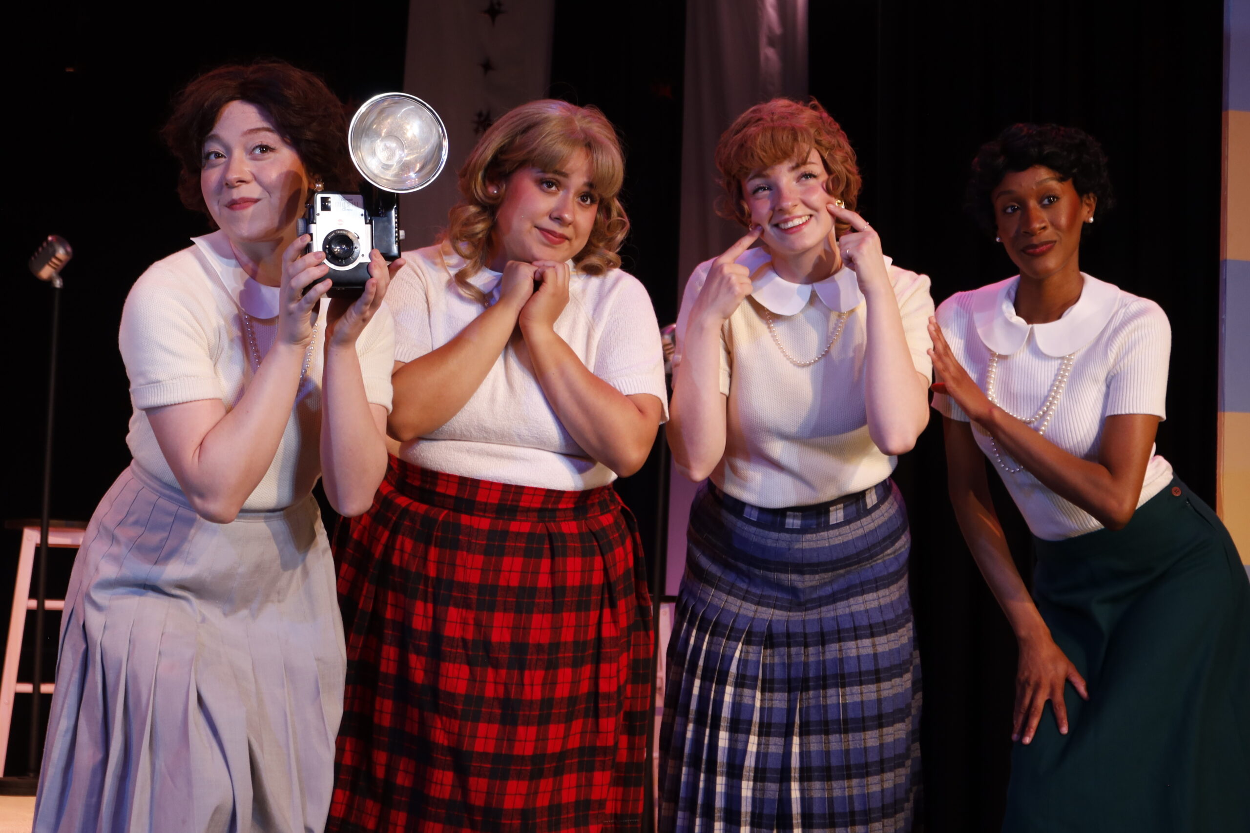 Four women dressed in 60s attire posing to take a picture